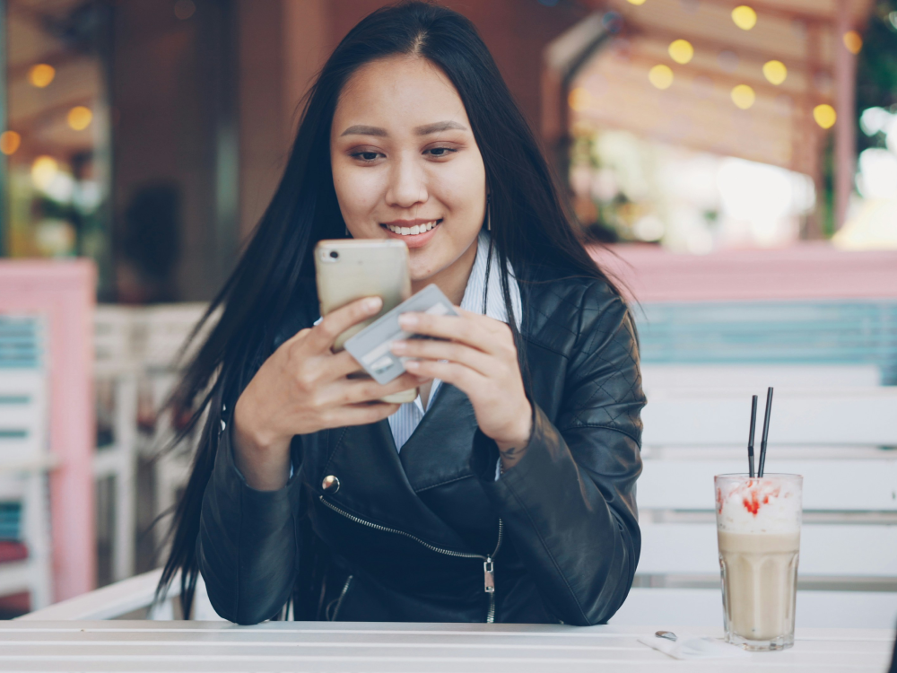 A Canadian woman who must made the minimum payment on her credit card, smiling, knowing that it won't put a negative mark on her credit score.